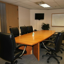 Professional meeting room with a wooden table, whiteboard, and wall-mounted monitor.