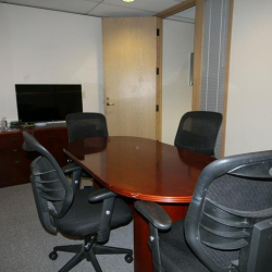 Intimate meeting space with a round mahogany table and comfortable rolling chairs.