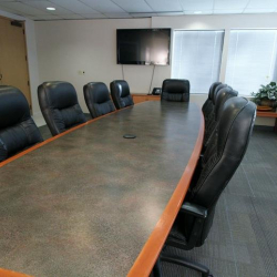 High-end conference table surrounded by rows of professional black leather seating.