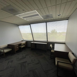 Open office space with three desks and expansive exterior windows.