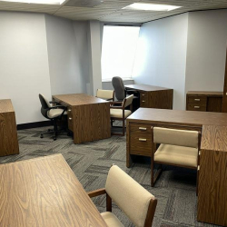 Spacious shared office area with multiple wooden desks and ergonomic chairs.