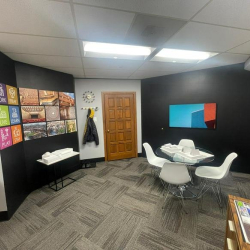 Modern meeting room with a round table, white chairs, and a black accent wall.