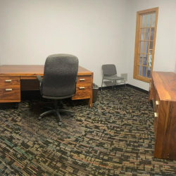 Private office suite with wood furniture and large patterned carpeting.
