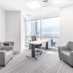 Bright private office suite with grey armchairs and floor-to-ceiling windows.
