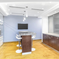 Office kitchen area with a high bar table and coffee machine.