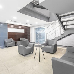Modern reception lobby with grey seating and a sleek metal staircase.