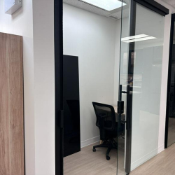 View into a private glass-enclosed work booth with an ergonomic black chair.