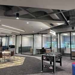 Office breakout area with a foosball table and views into glass-walled private offices.