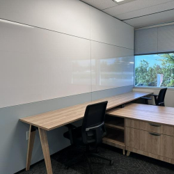 Bright workspace with a long wooden desk set against a full-wall whiteboard.