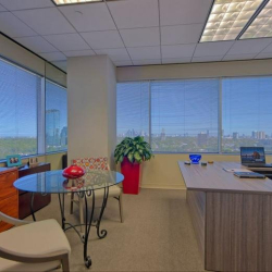 Professional conference room with a white rectangular table, tan chairs, and a wall-mounted monitor.