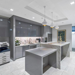 Covered building entrance featuring glass double doors, dark stone pillars, and recessed lighting.