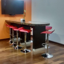 Employee breakroom featuring a high-top dark wood counter, red bar stools, and a wall-mounted TV.