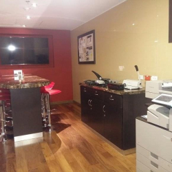 Office utility area with a high-top work table, red stools, and a large professional copy machine.