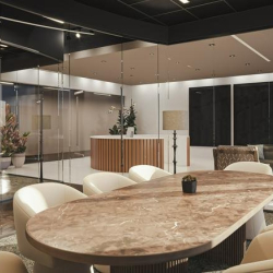 Professional meeting space with a large oval stone table and soft cream armchairs.