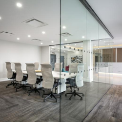 Glass-walled conference room with a large white table and white chairs at 500 – 224 West Esplanade.