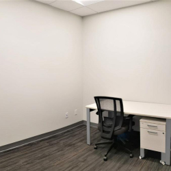 Small private office suite with a white desk and ergonomic mesh chair.
