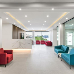 Spacious reception area with colorful red and teal armchairs and a marble counter.