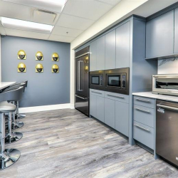 Modern breakroom with grey cabinets, bar seating, and stainless steel appliances.
