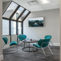 Casual meeting area with teal rocking chairs and a round table by a sloped window.