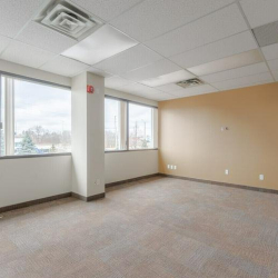 Open office space featuring a central pillar and a beige feature wall.
