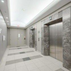 Clean elevator bank with marble tiling and bright ceiling lighting.