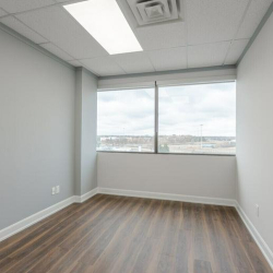 Unfurnished office space with wood-style flooring and large windows.