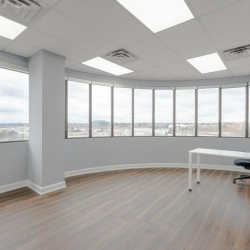 Bright corner office with a wrap-around window wall and light flooring.