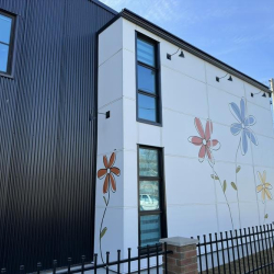 Corner view of the building showing murals and black metal fencing.