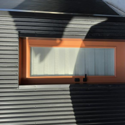 Entrance door with a distinct orange frame and horizontal glass panes.