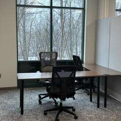 Bright office suite with two desks and a large window looking out onto a wooded area.