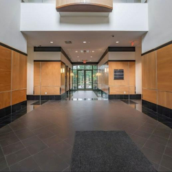 Spacious building lobby with warm wood paneling and sleek black flooring.