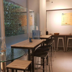 Shared break area with high tables, bar stools, and views of lush greenery.