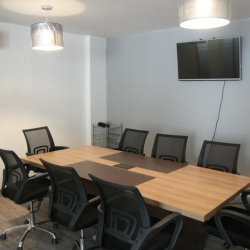 Professional conference room with a large wooden table and wall-mounted screen.