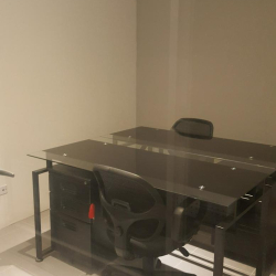 Minimalist two-person private office with glass-top desks and frosted glass partitions.