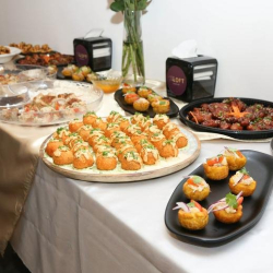 Buffet-style catering spread with various appetizers on a white tablecloth.