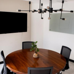 Small meeting room with a round wooden table and wall-mounted television.