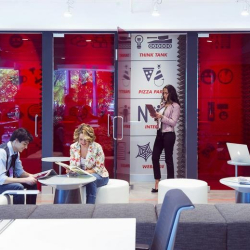 Modern lounge area featuring red glass partitions and white seating pods.