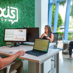 Wide view of a modern common area with a green moss wall and blue branding.