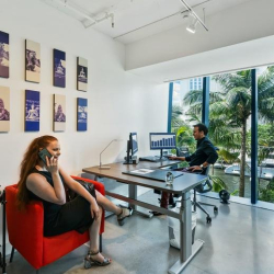 Light-filled office with a red armchair and views of palm trees.