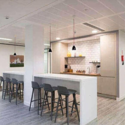 Stylish office kitchen and break area with high-top tables and modern pendant lighting.