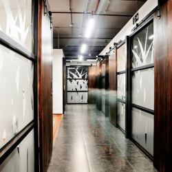 Vibrant lounge area with a yellow sofa, neon wall art, and industrial ceiling details.