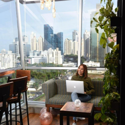 Shared kitchen and lounge area with wooden seating and floor-to-ceiling city views.