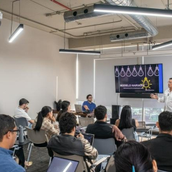Bright breakout space with a comfortable chair and tripod floor lamp against a city backdrop.