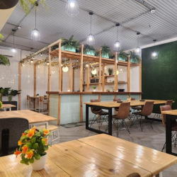 Bright shared workspace featuring wooden tables and a lush artificial plant wall.