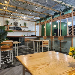 Break area and kitchenette with wooden cafe tables and overhead string lights.