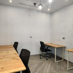 Shared office suite with white faux-brick walls and three light wood desks.