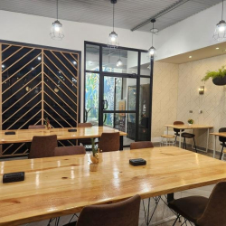 Open-plan coworking area with long timber tables and industrial pendant lighting.