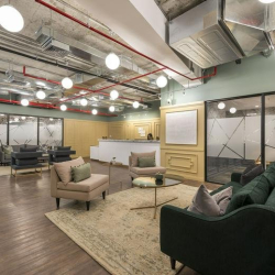 Modern coworking space with long wooden desks and office chairs, Avenida Manuel Olguín 327, Lima, Peru.