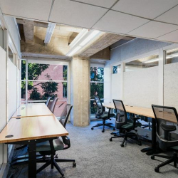 Minimalist private office with white walls, four desks, and natural light.