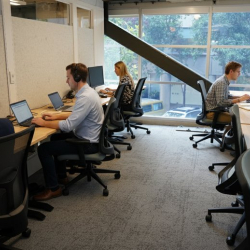 Small two-desk private office with a large window looking out at trees.